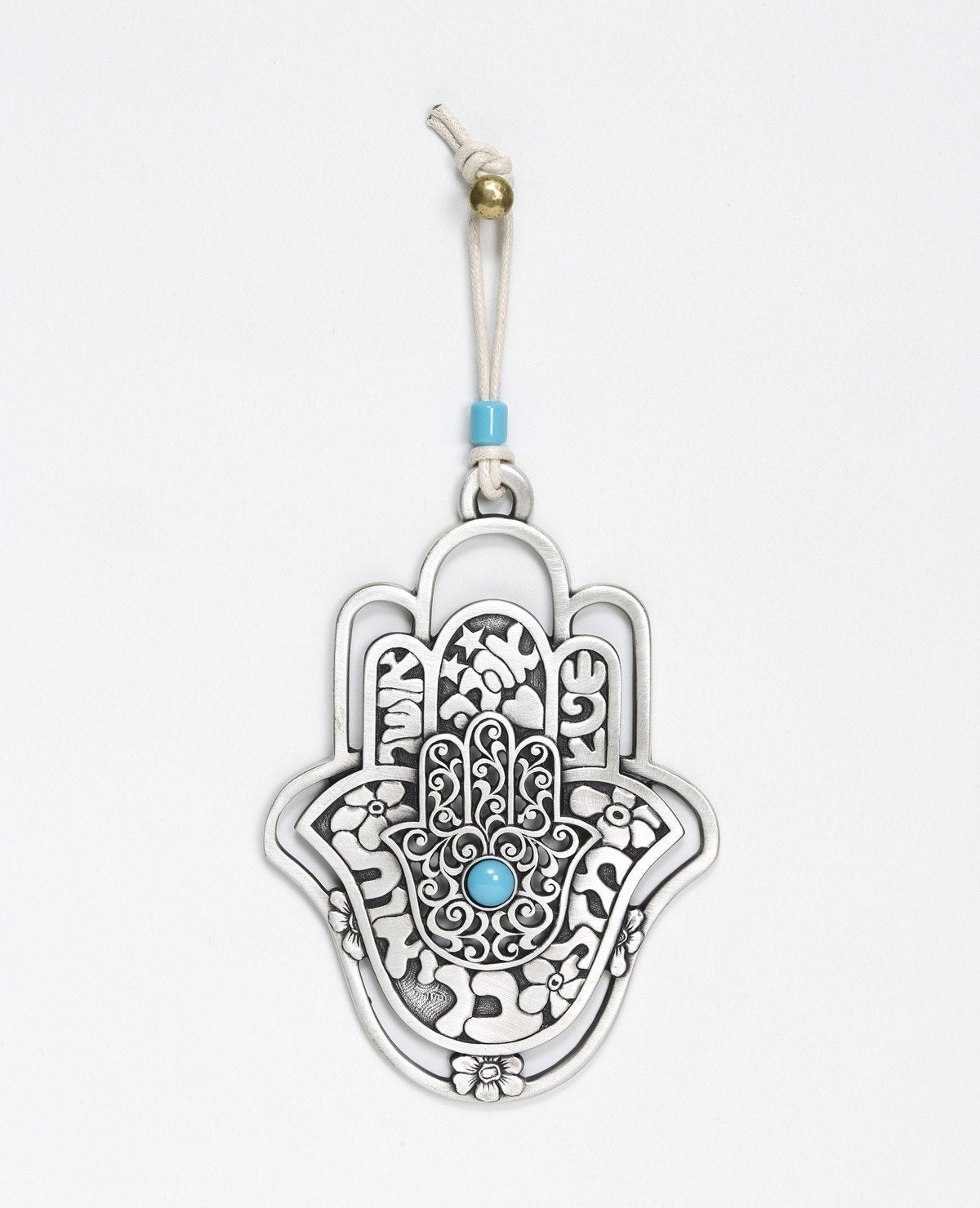 A hanging Hamsa ornament, designed in exquisite beauty: a Hamsa within a Hamsa within a Hamsa. The outer one - a hollow frame decorated by delicate flowers. The middle one - all embossed words of blessing - for abundance, luck, health, happiness and love. The inner one - filigree decoration with a turquoise stone at the center. The ornament is coated in sterling silver and comes with a faux leather string deocorated by a turquoise bead. An impressive and very meaningful gift that is a pleasure to grant to o