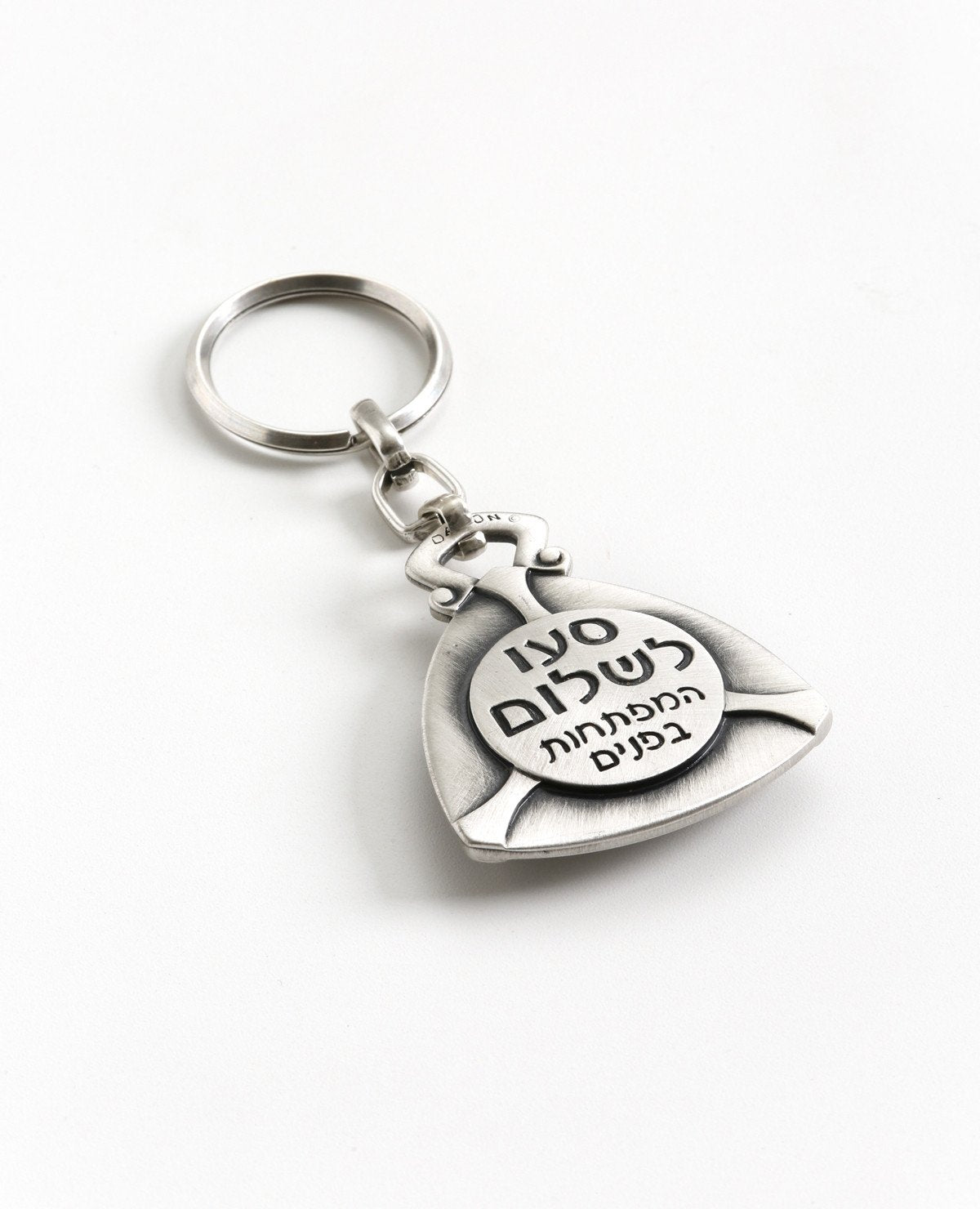 A famous comic Hebrew expression: "drive safe, the keys are inside". A cute keychain that reminds Israelis of funny times. Designed as a triangular plate, on one side is an embossed circle on which the sentence "drive safe the keys are inside" appears. On the other side is a compass, to never lose the way. The most observant people will also notice a peace sign. The keychain is coated in sterling silver and is strong and reliable. A gift that is fun to grant! It includes a blessing, direction, and a smile.