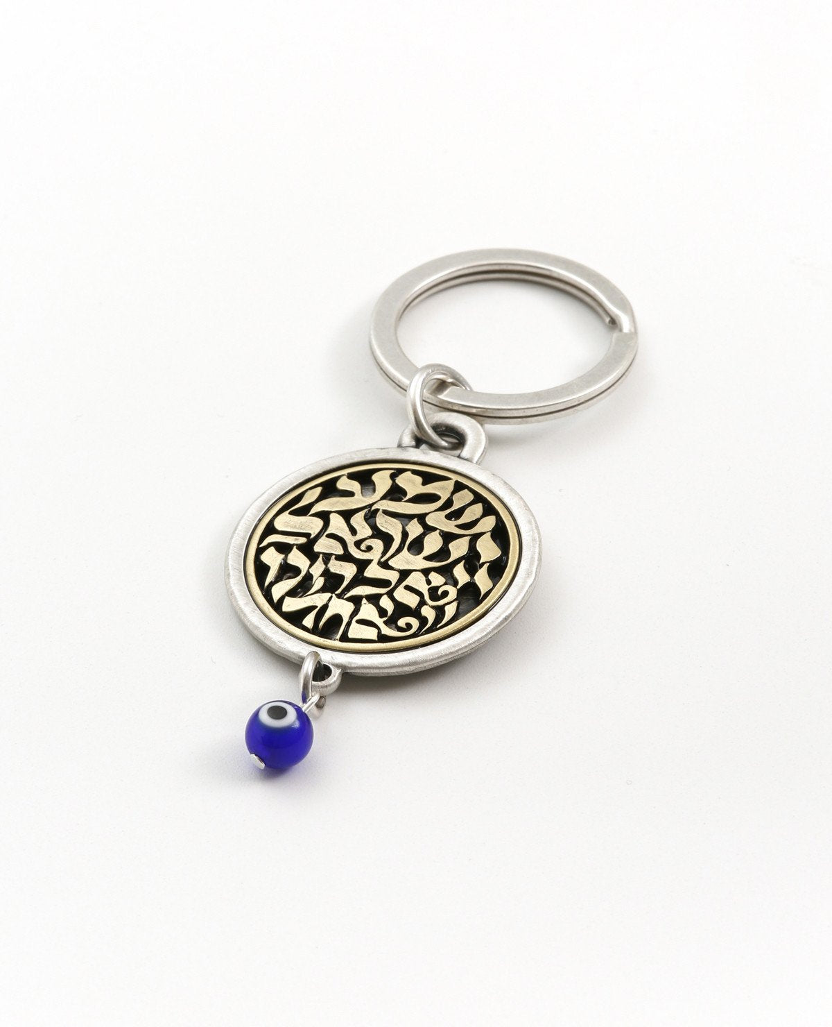 A keychain that touches the soul of any Jew. Designed as a circle, with the embossed words "Hear O Israel, the Lord our god, the Lord is one" in brass coated letters on a black background on one side. Engraved on the other side is the sentence "with the greatness of thy powerful right hand", decorated by a Hamsa with an eye. At the bottom of the circle hangs a blue eye - against the "evil eye". The words "Shema Israel" remind the people of Israel that God is the one and only and is regarded in Judaism as t