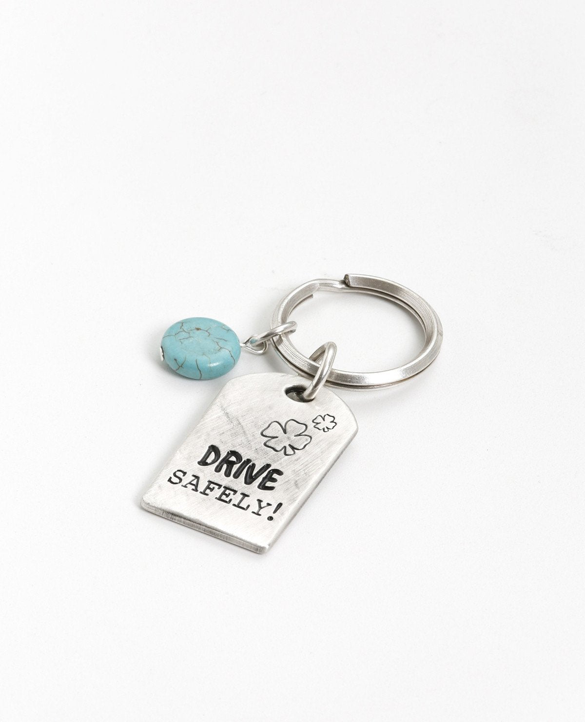 Drive carefully! Somebody loves you and cares about you. An impressive and excitingly designed keychain in the shape of a rectangular plate. One side has the words "Drive Safely" written on it, and on the other side the words "Someone loves you". Next to the plate hangs an impressive round turquoise stone. The keychain is coated in sterling silver and is strong and reliable. An exciting gift for him or for her with an important reminder: take care when driving, because somebody loves you. Length: 7 cm Wid