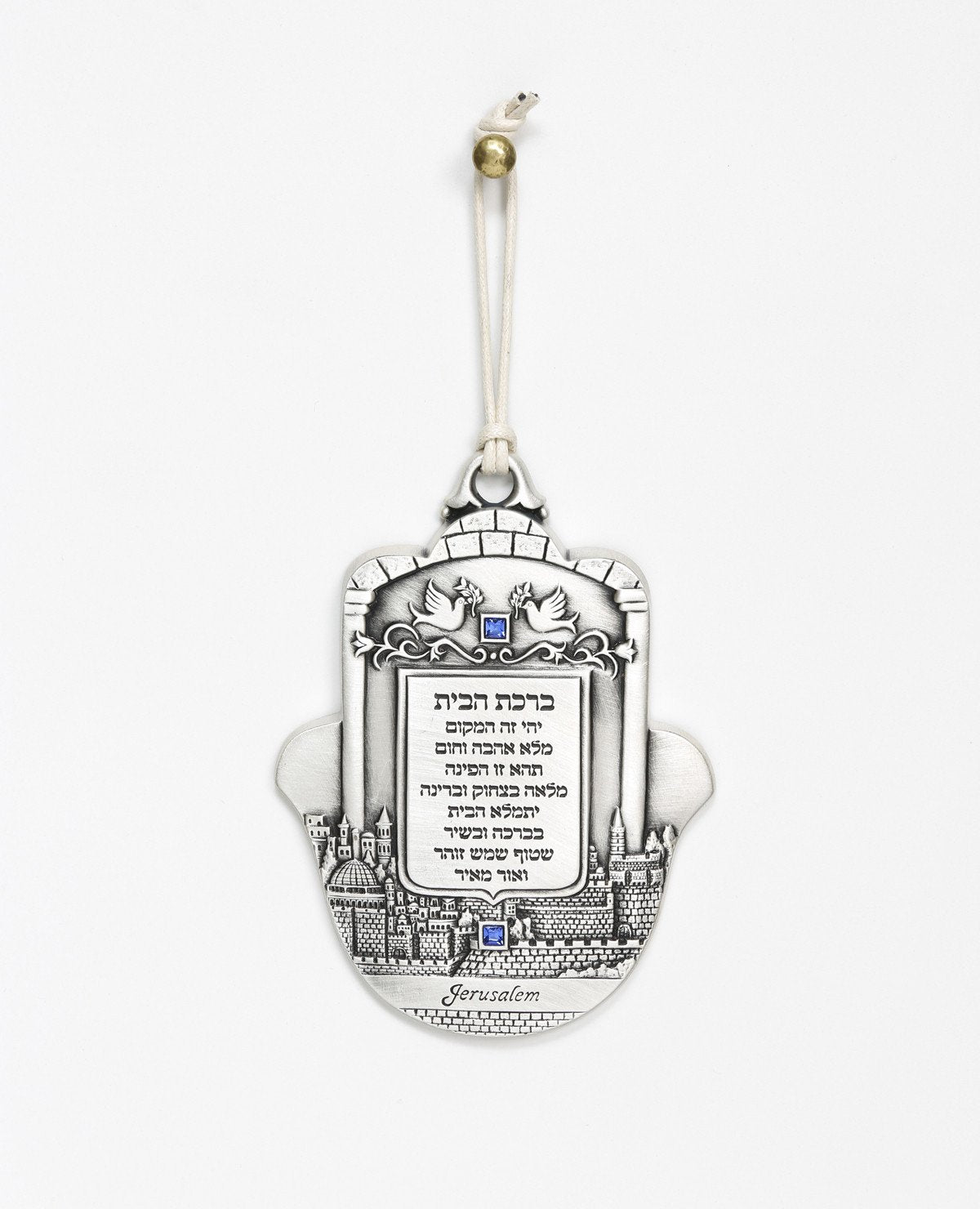 An impressively designed and uniquely decorated Hamsa hanging ornament coated in sterling silver. Decorated with an embossed image of Jerusalem and a pair of peace doves with an olive branch, alongside blessing words of love, joy, laughter and light for the home. Makes a thoughtful and loving gift that will brighten up any house. The Hamsa is embedded with blue Swarovski crystals and a natural colored faux leather string. 
Comes also in your choice of azure embedding. Additional languages available: English