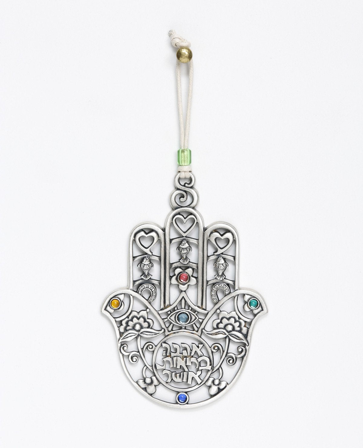 A Hamsa hanging wall ornament, gently designed and full of presence. The more you look at it the more and more you discover details and motifs that intensify its beauty. You can find motifs of a heart, a horseshoe, and a fish... Can you spot the birds? The special cut which creates a variety of different shapes, the intertwined flowers, the coloful stones... in short, a medley of designs and blessings in words and symbols. A gift you will want to gaze at more and more and give again and again. The ornament 