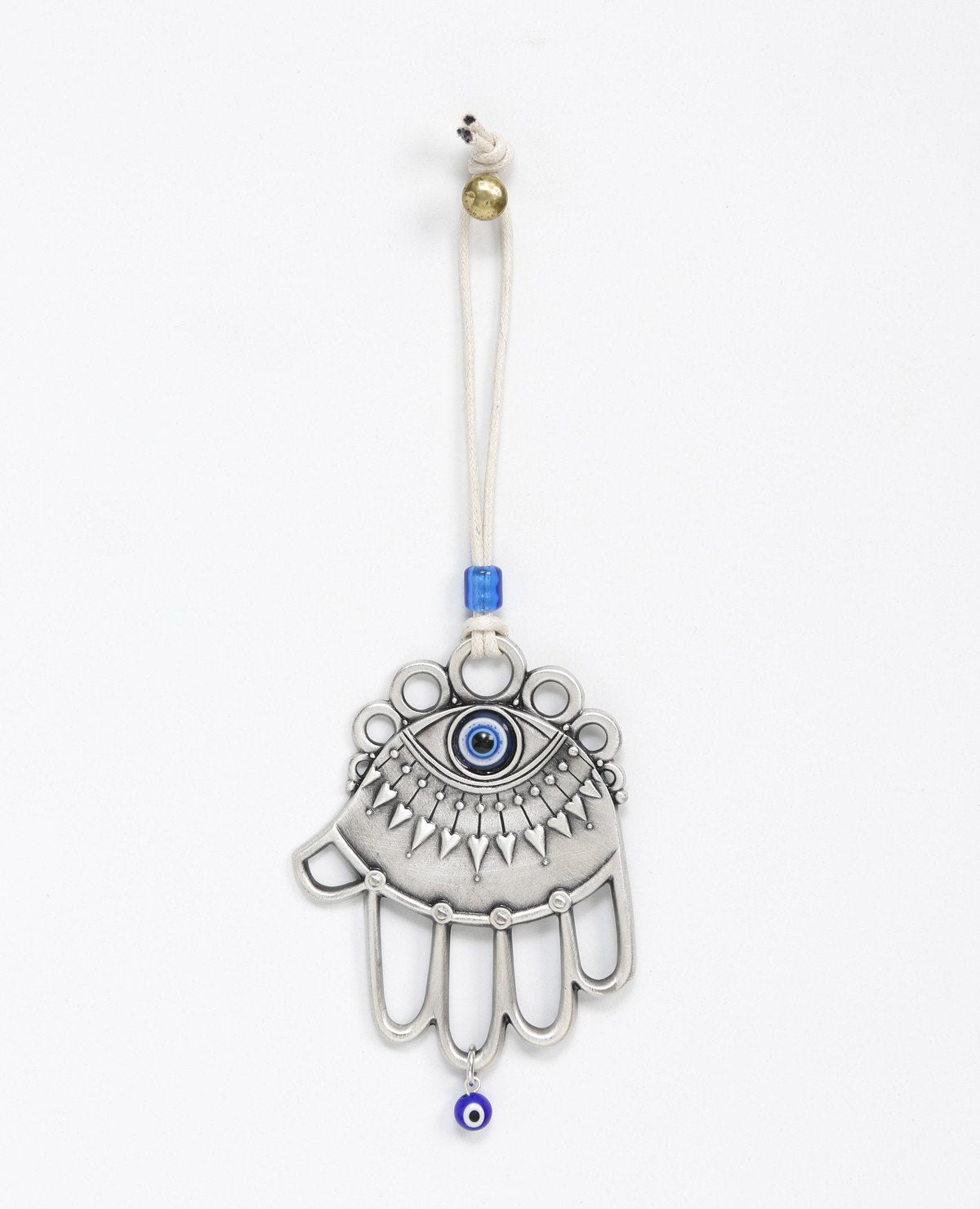 A one of a kind hanging Hamsa ornament. It is designed with a combination of different styles, some of which are hollow, while others are solid decorated surfaces. Embedded at the top of the Hamsa is a large blue eye, decorated by a lower eyelash in the shape of heart arrows. The fingers of the Hamsa are hollow and at their bottom hangs a small blue eye. The ornament is coated in sterling silver and comes with a faux leather string for hanging, decorated by a blue bead. 
The blue eye is considered a charm a