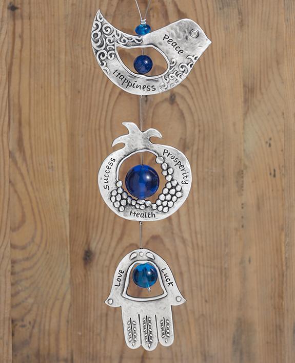A graceful seven blessings hanging ornament coated in sterling silver, that brings joy and blesses. The ornament is made up from three motifs from the world of charms: a bird, a pomegranate and a Hamsa. All are connected to each other by a thin silver coated string decorated by blue beads, with a loop at the end for hanging. Each motif is designed with unique decorative embossments, and together create a charming and harmonic whole. Written on each one of the shapes are words of blessing, in Hebrew on one s