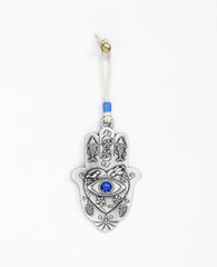 A hanging Hamsa ornament packed with goodness! The Hamsa is coated in sterling sivler and comes with a natural colored faux leather string for hanging, decorated by a blue bead. At the center of the Hamsa is a big heart with an embossed eye inside embedded with a blue colored stone (against the "evil eye"). Above the eye are chirping birds (of peace and love). The Hamsa is decorated with embossed fish (for luck), as well as vine leaves and grape clusters (for abundance). What else could we ask for? Just the