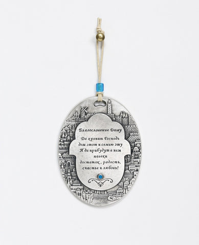 A spectacularly beautiful hanging Home Blessing ornament in Russian, in the shape of an oval plate. The plate is embedded around its edges with an outline of the sights of Jerusalem, and in the center a Hamsa upon which appear blessing words for love, friendship, joy, health, happiness and peace. Makes a very welcoming gift for the home intended for the people we hold dear, far or near. The hanging ornament is coated in sterling silver and embedded with a blue colored Swarovski crystal. Comes with a natural