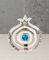 This pomegranate ornament is always in motion. The clever and impressive design for this ornament is made from three circular frames. The first is designed as a hollow pomegranate with two rotating circles at its center that spin on a central axis. On both the inner and outer circles appear an embossed image of the beautiful Jerusalem landscape. The axis in the center is threaded with colorful beads for decoration. The thin silver string that connects between the circles is pulled to beyond the crown of the