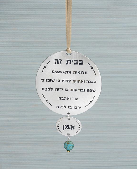 A hanging Home Blessing ornament in the form of two circles coated in sterling silver with a turquoise colored bead. The words of blessing will bestow the house with love, health, kinship, abundance and fulfilled dreams. A joyful and thoughtful gift that blesses anyone who may receive it. Comes with a brightly colored satin string for hanging.  Length: 13.7 cm  Width: 9 cm