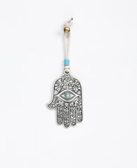 A hanging Hamsa ornament decorated with a filigree engraving, coated in sterling silver and embedded with a turquoise colored stone. The Hamsa hangs from a leather string which is decorated by a turquoise colored bead. The Hamsa is a well known good luck charm that contains qualities that protect from the "evil eye". That's why it makes such a sweet and joyful gift to hang on the wall, the car mirror, and in any place where we ask to grant protection and a good blessing.  Length: 9 cm  Width: 5 cm