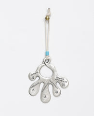 An open hand Hamsa wall ornament that hangs from a natural colored faux leather string decorated by a turquoise colored bead. The Hamsa is coated in sterling silver and each finger has a blessing engraved on it in English and Chinese. The blessings are from the world of Feng Shui, the ancient Chinese philosophy which represents the way of peace and harmony. Luck, abundance, harmony, peace, longevity, joy and more joy, these are the loving blessings which you can grant to whoever will receive this charming g