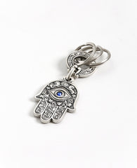 A double sided Hamsa keychain coated in sterling silver. On one side is a big eye embedded with a blue colored Swarovski crystal and embossed lions. On the other side are embossed birds, pomegranates, fish and grapes. The whole Hamsa is decorated in a filigree like style. The connecting links and the key rings are massive and strong. It's fun to connect our most important keys to it and most definitely to grant our loved ones with such a beautiful Hamsa, blessed with the many icons of good fortune, protecti