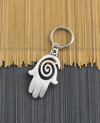 A charming and uniquely designed Hamsa shaped keychain which incorporates a full design with the empty spaces within the spiral. The Hamsa is coated in sterling silver and is slightly concave. It is so beautiful that you can just keep staring at it over and over, feel its different textures and sense the blessing within. A strong and reliable keychain that makes a great gift for your loved ones.  Length: 7 cm  Width: 4 cm