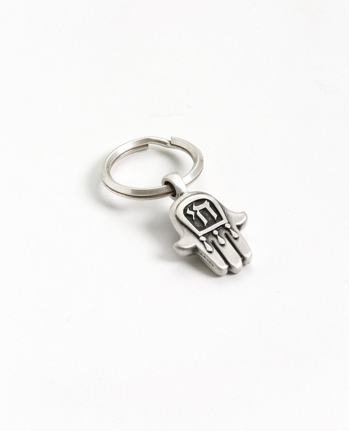 A small Hamsa shaped Chai keychain that carries a blessing with it. 
On one side of the keychain is a Hamsa decorated with a round blue colored stone, and on the other side the blessed "Chai" letters are engraved, symbolizing protection.
Makes a joyful gift for any occasion and for anyone who we may want the keys to their life be kept on a blessed and beautiful keychain like this one.  Length: 4 cm  Width: 2 cm