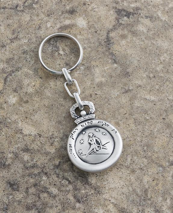"There is no place too far"! That is the inspiring message of this charming keychain. An exciting and unique design on this round keychain. One side is engraved with the image of The Little Prince surrounded by stars, and on the other side is a compass. 
The keychain is coated in sterling silver and hangs from a strong and reliable linked chain. 
A special and marvelous gift to grant to anyone you hold dear, in order to bless them at every moment with full confidence in themselves, and a compass to show the