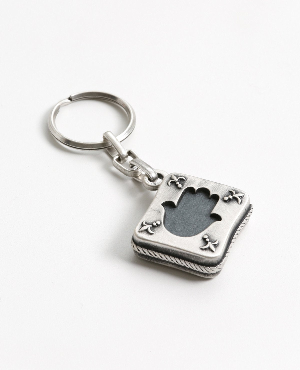 Tehillim is always with you. An exciting and elegantly designed keychain coated in sterling silver. Fashioned in the form of a small silver envelope with the book of Tehillim inside. The outline is designed on both sides as a frame with a hollow Hamsa shape in the middle, through which we can see the book on both its front and back sides. Feel safe and connected to your roots any time you have this wonderful keychain on you. You will feel even better when you grant it with love to the dearest people in your