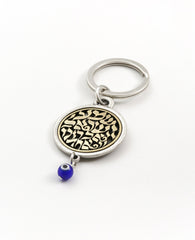 A keychain that touches the soul of any Jew. Designed as a circle, with the embossed words "Hear O Israel, the Lord our god, the Lord is one" in brass coated letters on a black background on one side. Engraved on the other side is the sentence "with the greatness​ of thy powerful right hand", decorated by a Hamsa with an eye. At the bottom of the circle hangs a blue eye - against the "evil eye". The words "Shema Israel" remind the people of Israel that God is the one and only and is regarded in Judaism as t