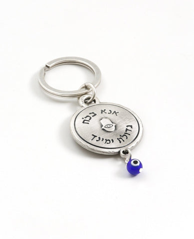 A keychain that touches the soul of any Jew. Designed as a circle, with the embossed words "Hear O Israel, the Lord our god, the Lord is one" in brass coated letters on a black background on one side. Engraved on the other side is the sentence "with the greatness​ of thy powerful right hand", decorated by a Hamsa with an eye. At the bottom of the circle hangs a blue eye - against the "evil eye". The words "Shema Israel" remind the people of Israel that God is the one and only and is regarded in Judaism as t