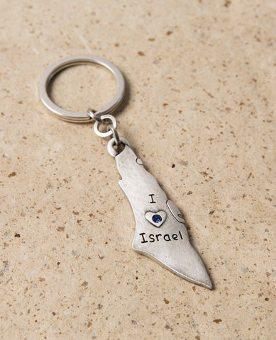 A charming keychain for Israel lovers, in English and designed in the shape of a map of Israel. Engraved on one side are the words "I Love Israel" with a heart embedded with blue colored Swarovski crystals, and on the other side a flag of Israel. The keychain is coated in sterling silver and is strong and reliable. This reminder of the simple love for Israel makes a great gift for friends and family in Israel and abroad.   Length: 7 cm  Width: 2 cm