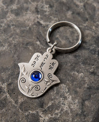 Someone is thinking good thoughts about you... A beautiful and unique Hamsa shaped keychain that will simply warm any heart. Engraved on one side of the Hamsa, between floral decorations, is the sentence "Someone is thinking of you". The other side is embedded with a round blue colored stone and is engraved with the words: "Love, Health, Happiness". We read your mind and designed this perfect gift especially for you, allowing you to pass on your loving thoughts in the most original way. The keychain is coat