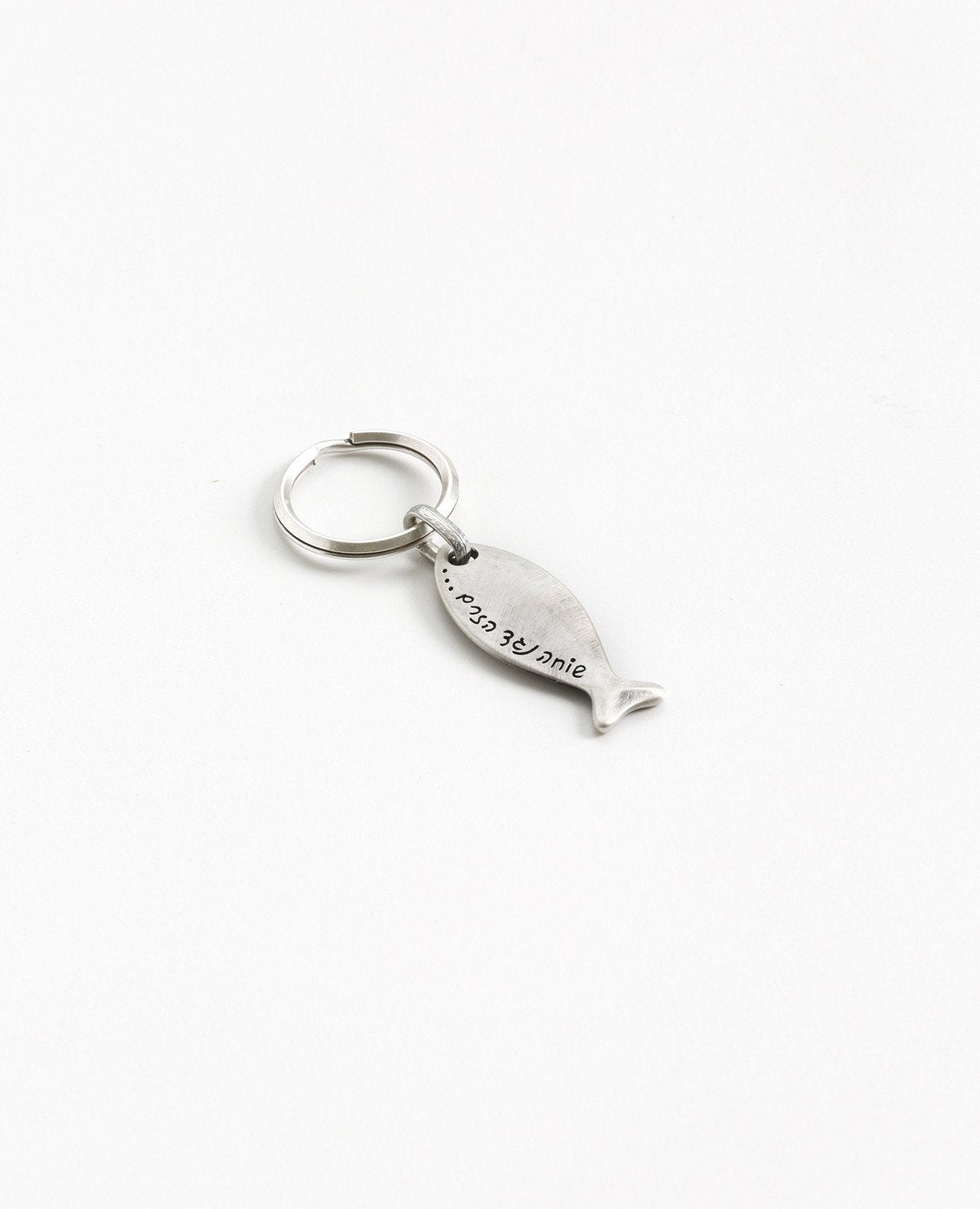 Sometimes we swim against the current to maintain integrity to our own personal statement. This fish shaped keychain is coated in sterling silver and has the words "swimming against the current" engraved onto it. The most suitable gift for when you want to remind someone close that it is allowed and even recommended to always be true to yourself and your inner voice. This keychain is motivating, strong and reliable.  Length: 6 cm  Width: 1 cm