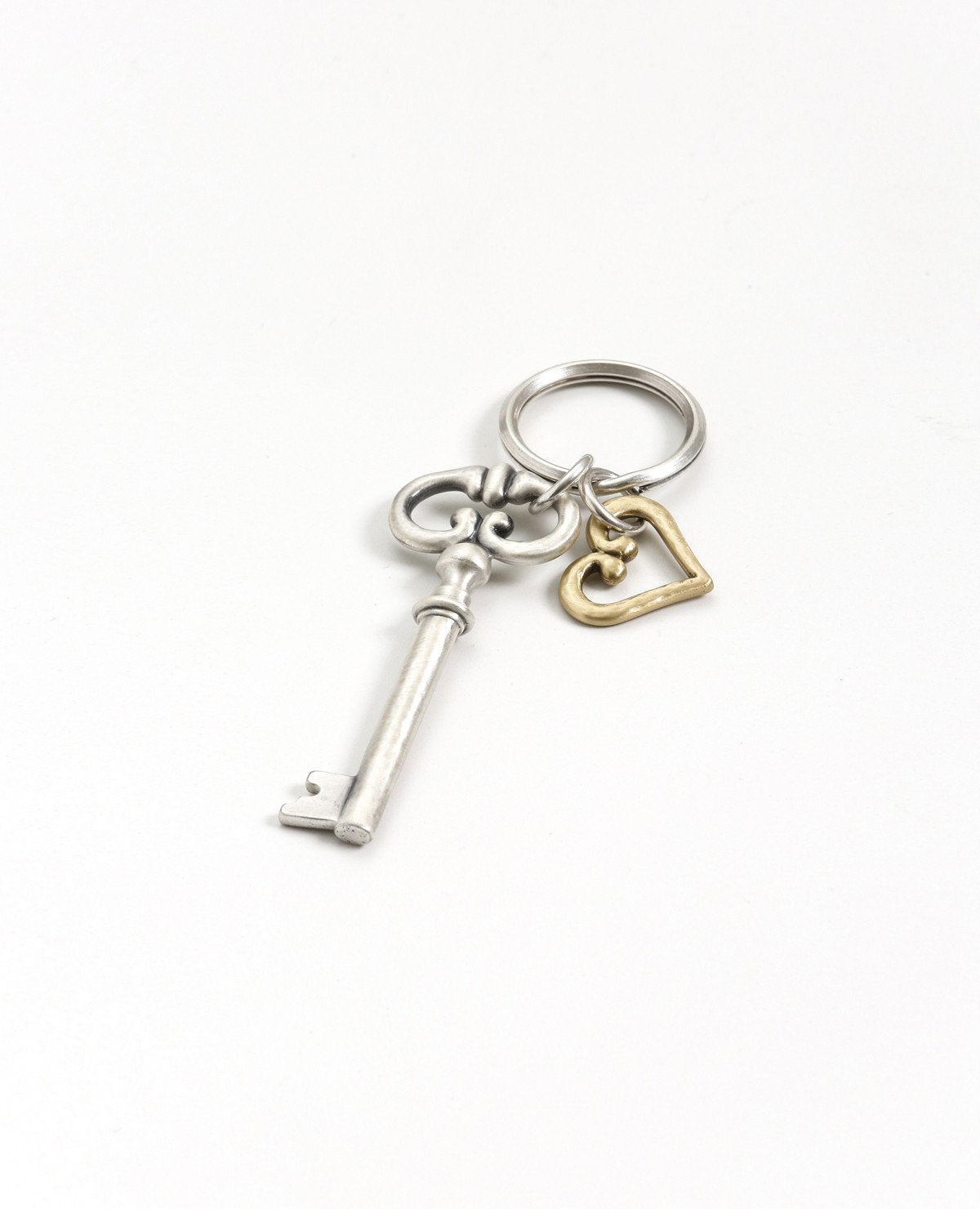 The key to the heart - because hearts and keys have gone together since the beginning of time. A charming and exciting keychain, the key is coated in sterling silver and has a classic design. The heart hangs next to the key, coated in golden brass. The keyring is strong and reliable. This is a timeless and classic present, suitable for any man or woman, in any occasion you wish to grant the gift of love.  Length: 10 cm  Width: 3 cm