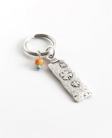 The gift that is most fun to give! A classically designed keychain - for him or for her. Shaped like an elongated rectangle with the words "Follow Your Dreams" on one side and embossed leaves decorating the other side. At the top of the keychain are two differently colored beads in the charming mix of orange and turquoise. The keychain is coated in sterling silver and is strong and reliable. A great gift to give to someone you love, anyone beginning a journey, or simply as a reminder that most important is 