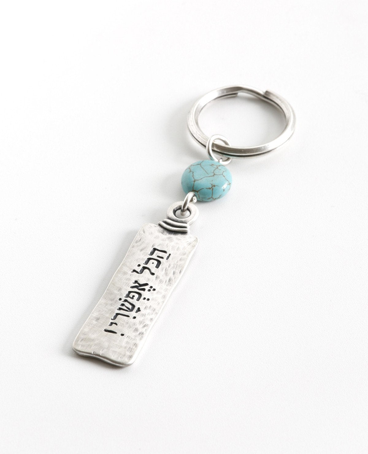 A classically designed keychain - for him or for her. Shaped like an elongated rectangle with the words "Everything is Possible!". Written on the other side are empowering words of hope and inspiration. A rounded turquoise bead at the top of the keychain completes the classic look. The keychain is coated in sterling silver and is strong and reliable. A gift that is always appropriate to give to a special person, in any opportunity, to remind that when you want something and believe - everything is possible!