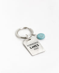 Drive carefully! Somebody loves you and cares about you. An impressive and excitingly designed keychain in the shape of a rectangular plate. One side has the words "Drive Safely" written on it, and on the other side the words "Someone loves you". Next to the plate hangs an impressive round turquoise stone. The keychain is coated in sterling silver and is strong and reliable. An exciting gift for him or for her with an important reminder: take care when driving, because somebody loves you.  Length: 7 cm  Wid