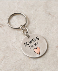 A keychain that directly touches the heart. Designed as a circle coated in sterling silver, one side has an embossed heart coated in brass with the words "Always In My Heart" written on it. The other side has drawings of tiny hearts all bunched together on the right side of the heart. The keychain is strong and reliable. Makes an exciting gift that says it all: always in my heart! Next to the beat of your heart there is always room for the heartbeat of your lover, best friend, mother, father, family member.