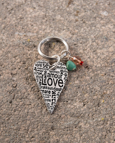A one of a kind keychain that crosses borders and brings hearts together. Designed as an elongated heart coated in sterling silver, upon which the word "Love" is written in different languages. Hanging on the keyring next to the heart are two colorful beads that add beauty and intrigue. The keychain is strong and reliable. Makes a great gift of love, anywhere and at any time, so that in the moment of truth, you won't find yourself at a loss for words...  Length: 9 cm  Width: 3 cm