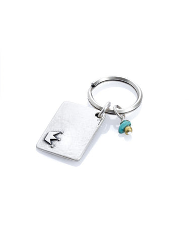 A simple and charming keychain, intended specifically for your prince. Designed as a rectangle coated in sterling silver with the word "Prince" written on one side, along with an embossed crown. On the other side is an embossed crown. Next to the rectangle hang two turquoise colored beads and a gold colored bead. The keychain is strong and reliable. Makes a great gift to embrace all the princes in your kingdom with a hug.   Length: 3 cm  Width: 4 cm