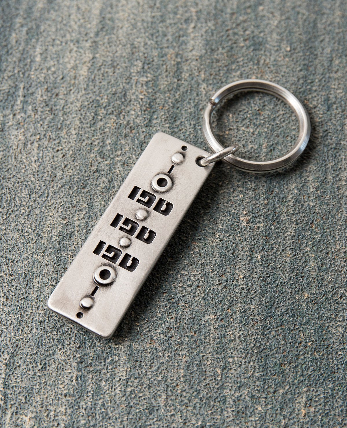 A gorgeous keychain that is always good to have in your pocket or your bag. Designed in the shape of a rectangle, one side has the words "Tfu Tfu Tfu" ("Touch Wood") written on it. Embedded on the other side is a beautiful blue eye, to ward off the "evil eye". Both sides display a similar artistic decoration. The keychain is coated in sterling silver and is strong and reliable. The most protecting gift you can give! Grant it with love to anyone important to you who you wish to protect from any harm that may