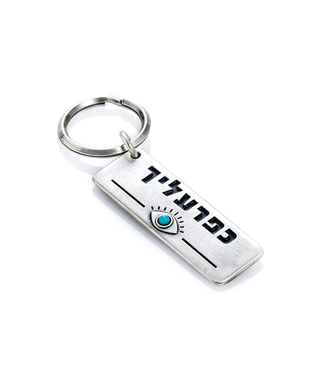 A whimsical keychain that is based on a local slang expression (a common term of endearment in Hebrew).
The keychain is designed as a rectangular plate with the words "Kapara On You" written on one side. Beneath is an embossed eye inlaid with a beautiful turquoise stone. Along the other side of the plate is an impressive and artistic graphic decoration.
The keychain is coated in sterling silver and is strong and reliable.
A gift that is fun to give, along with a big hug, to anyone we want to make sure they 
